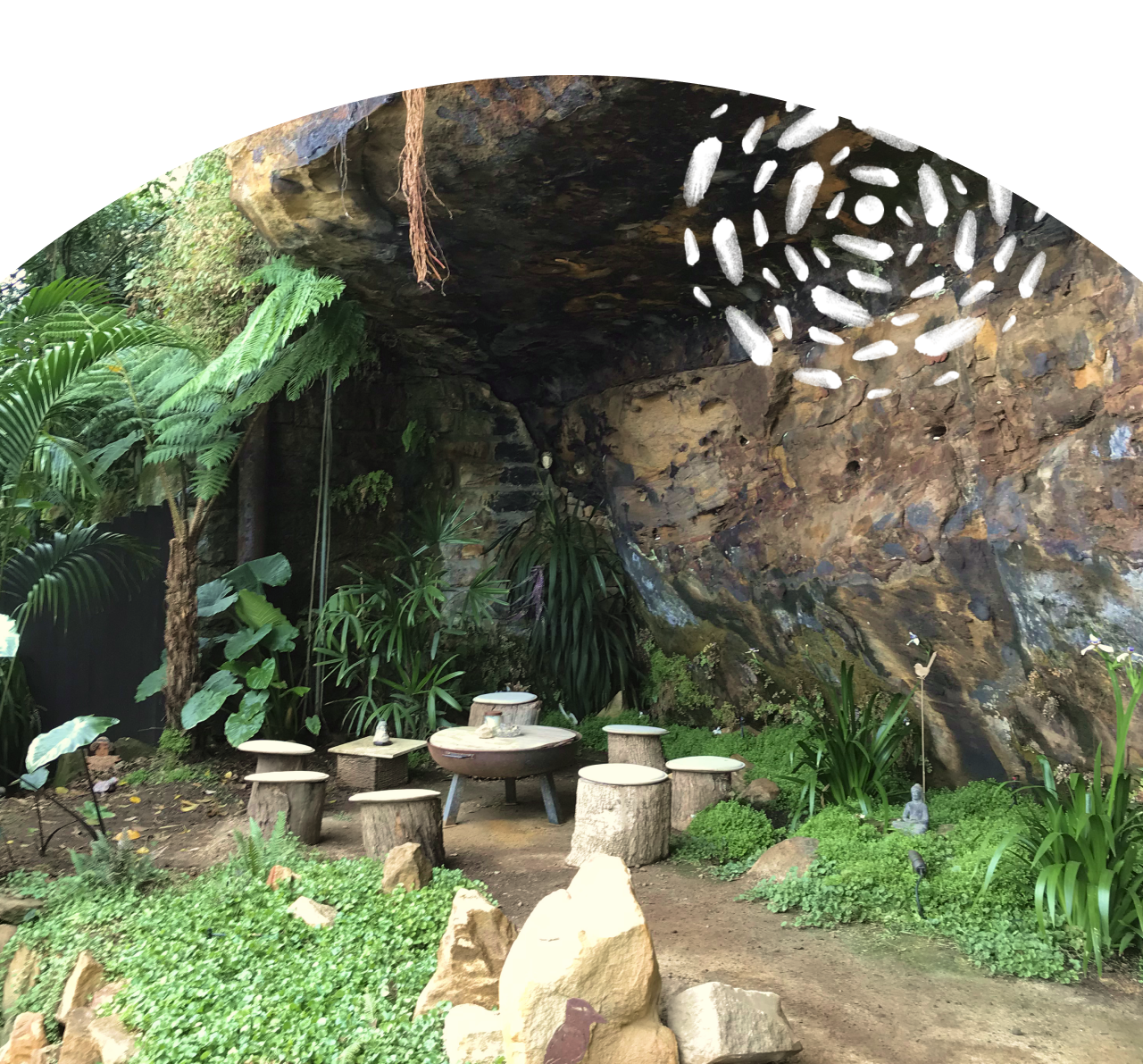 'Robyn's Nest' a gathering place at the base of a cliff, with a set of wooden log stools seated around a firepit in a circle.